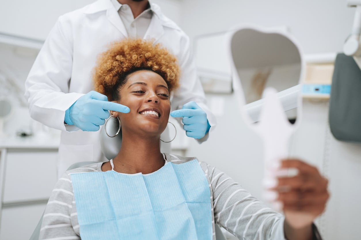 Young woman holding clear aligner at dental visit | Troy City Orthodontics in Fall River, MA